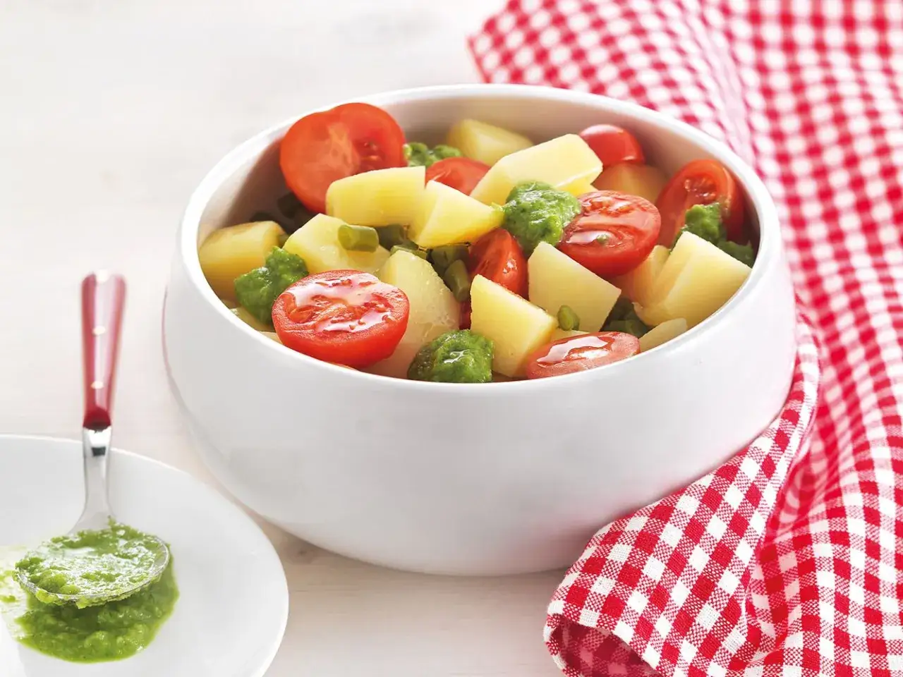 Un'insalata di patate estiva con pomodorini e piselli, condita con una salsa verde brillante. Perfetta per un picnic.