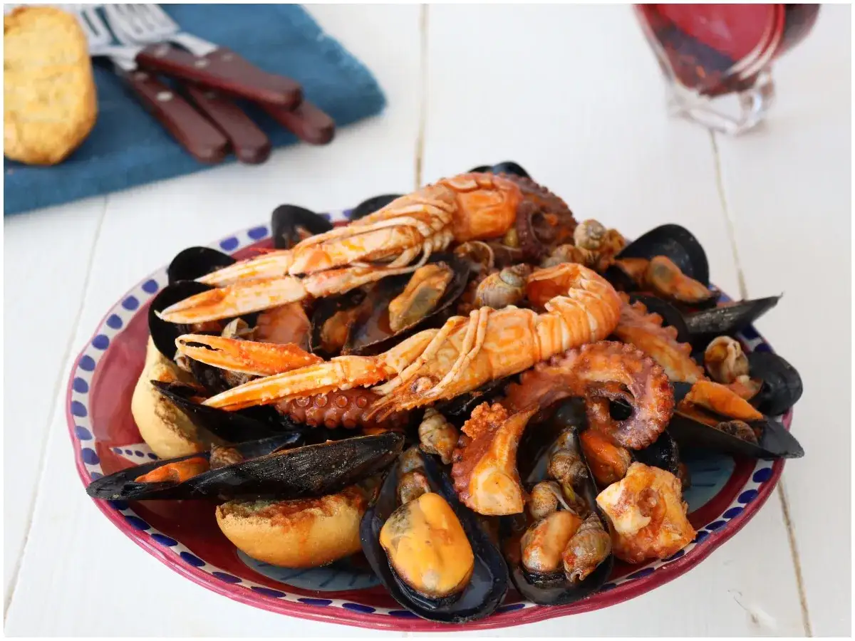 Un piatto invitante di zuppa di cozze, con scampi, polpo e pane tostato, pronto per essere gustato.