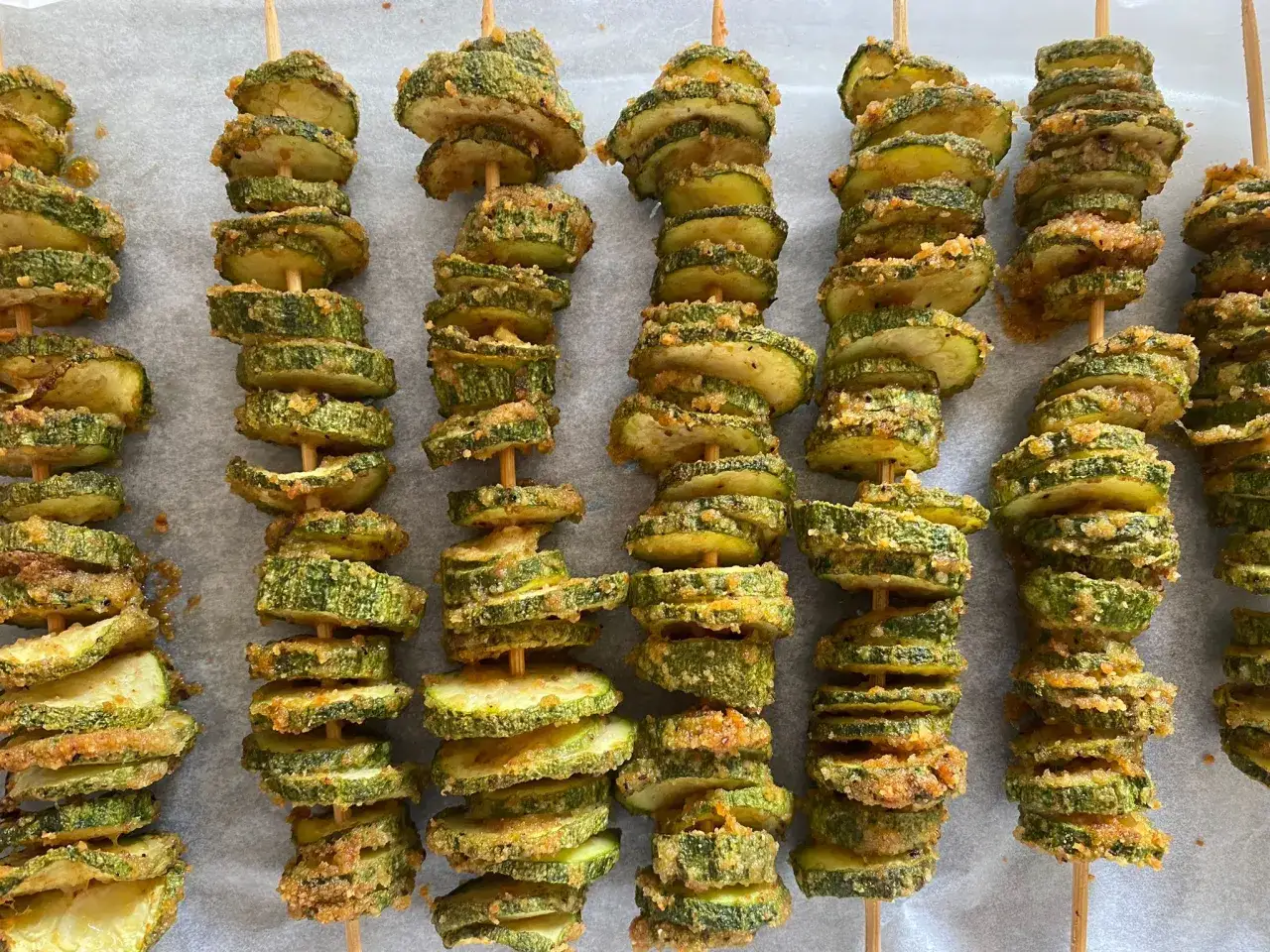 Spiedini di zucchine al forno, dorati e croccanti, pronti per essere gustati.