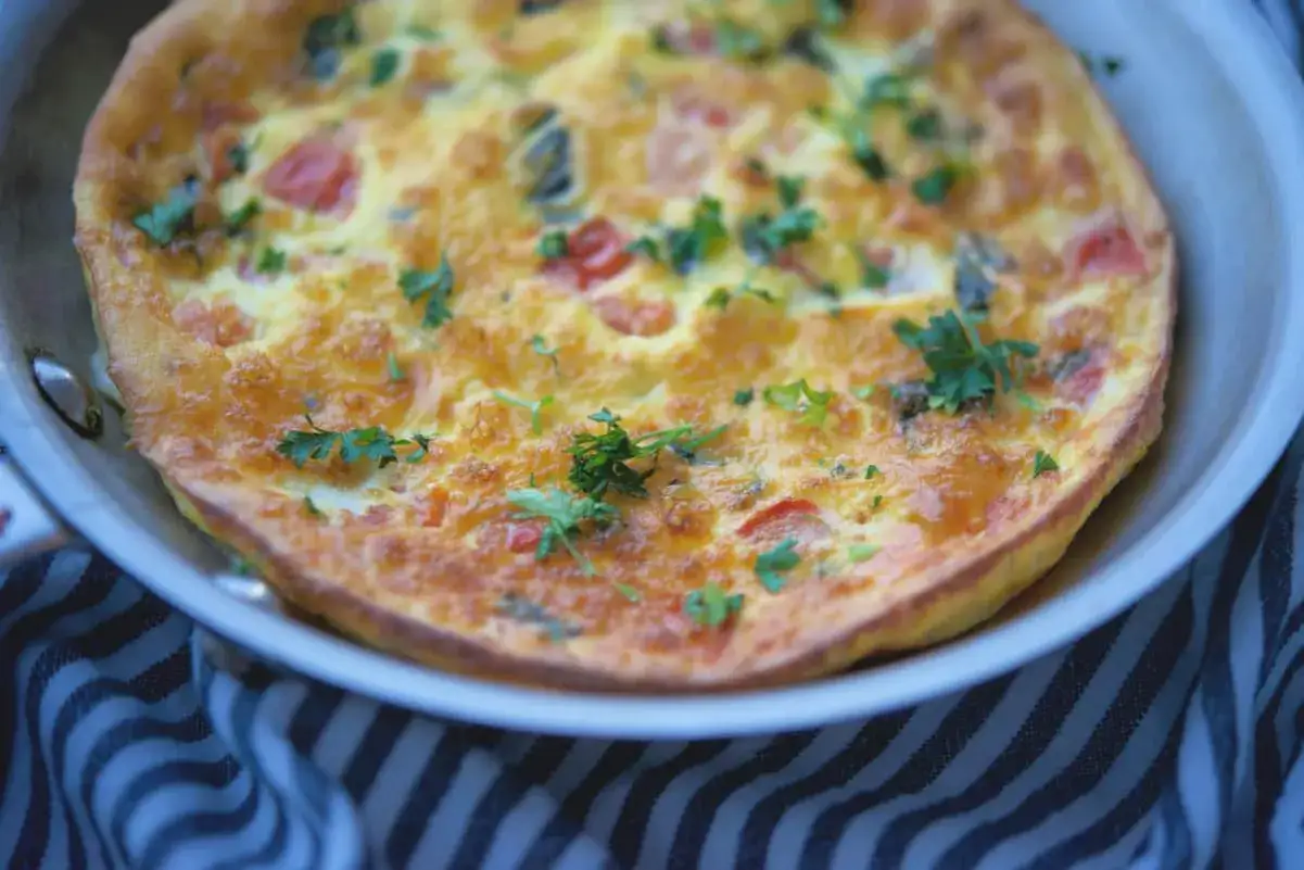 Frittata con mozzarella al forno, dorata e soffice, guarnita con prezzemolo fresco. Un piatto semplice e gustoso.