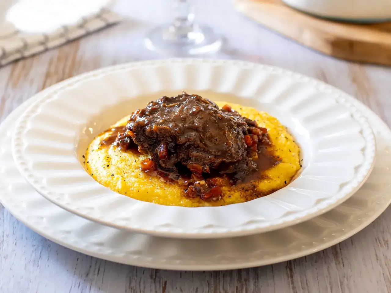 Guancette di maiale brasate su un letto di polenta cremosa, un piatto ricco e saporito.