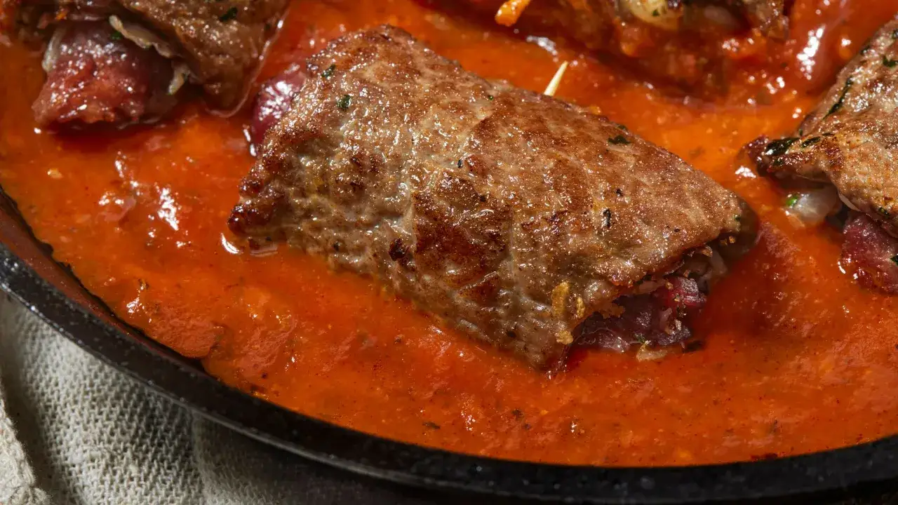 Involtini di carne in padella con sughetto rosso e saporito, pronti per essere gustati.