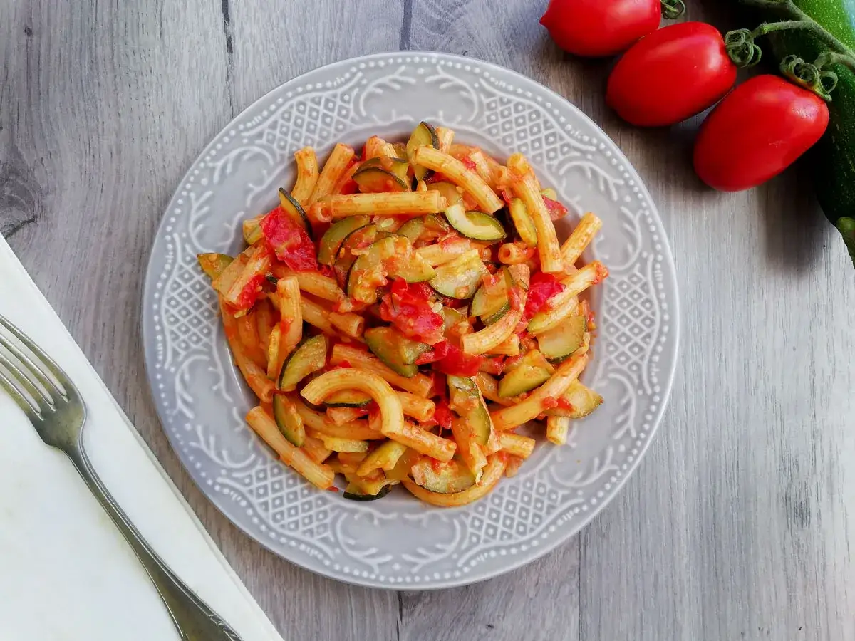 Piatto di pasta con zucchine e pomodorini, un classico primo piatto estivo.