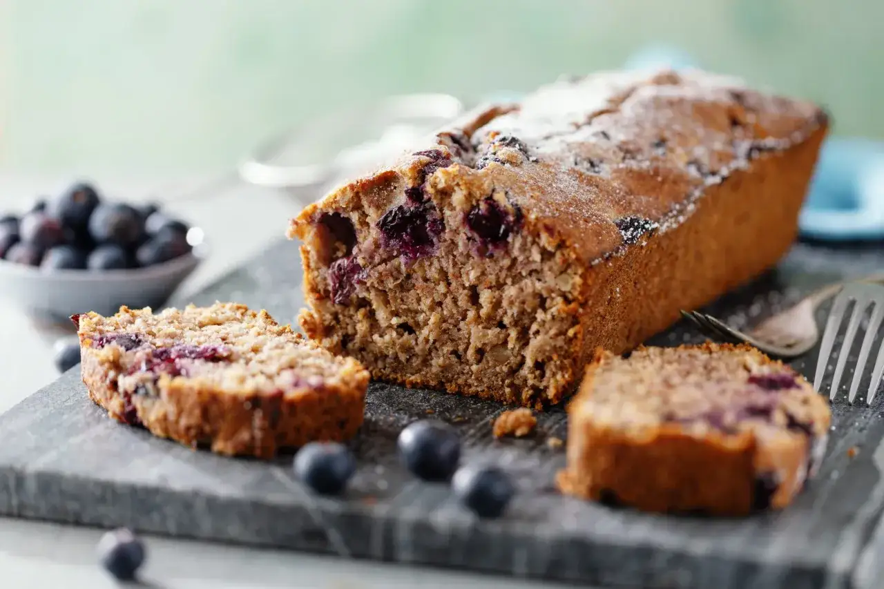 Delizioso plumcake ai mirtilli e fiocchi di avena, spolverato di zucchero a velo.