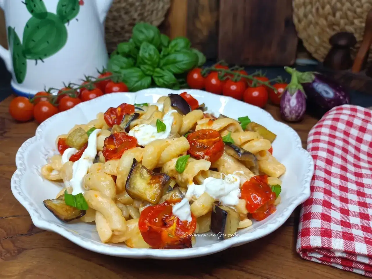 Un piatto di pasta fredda gourmet con melanzane, pomodorini e mozzarella fresca.
