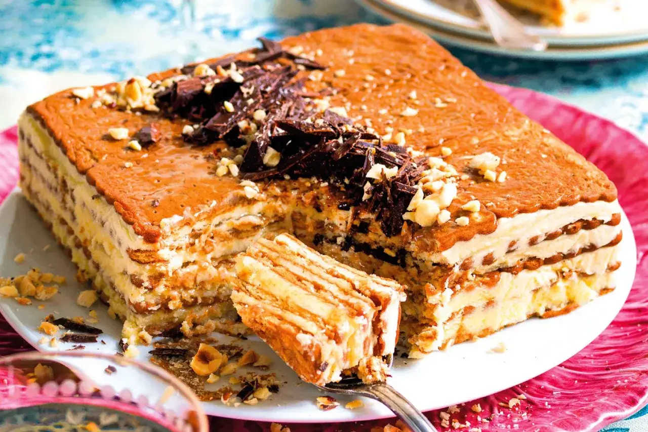 Delizioso dolce a strati con crema al burro, ricetta della nonna, guarnito con cioccolato e nocciole.
