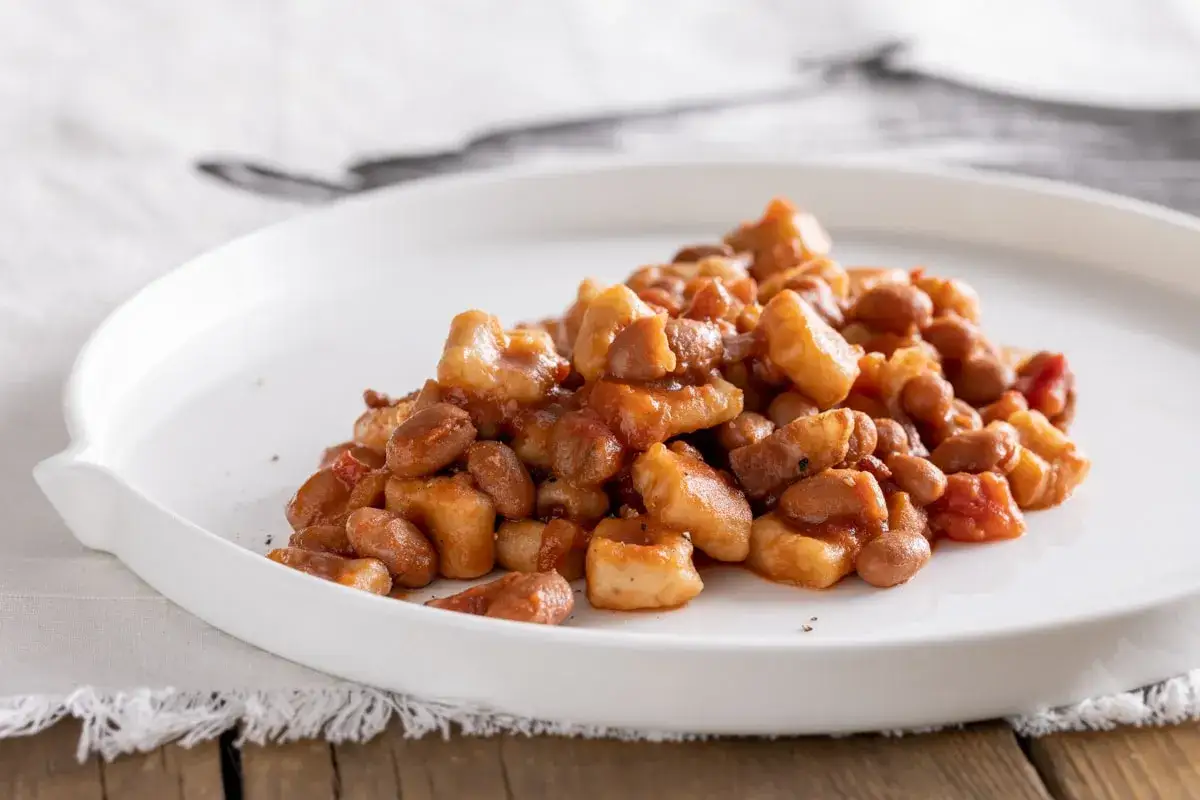 Un piatto di pisarei piacentini, pasta fatta in casa con fagioli e pomodoro, un assaggio della ricetta originale.