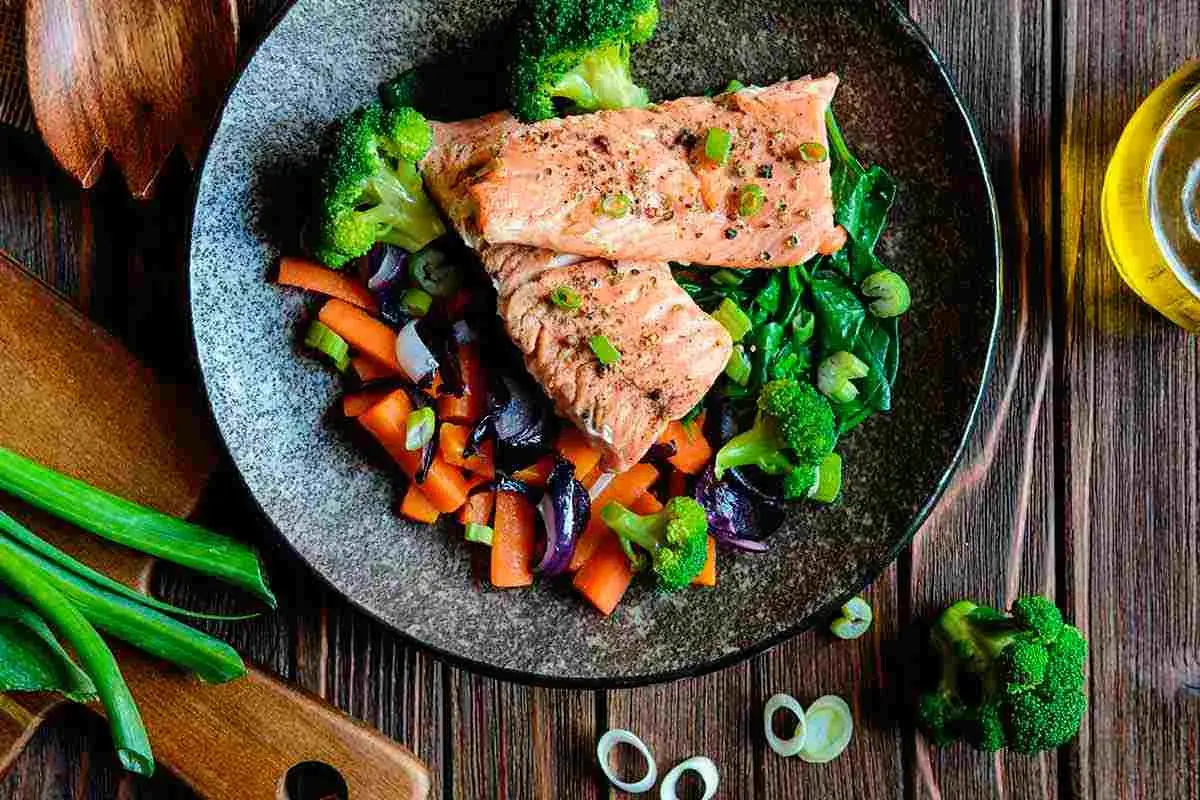 Salmone e verdure miste, un piatto sano e gustoso, preparato con la cottura al vapore. Broccoli, carote e spinaci accompagnano il pesce.