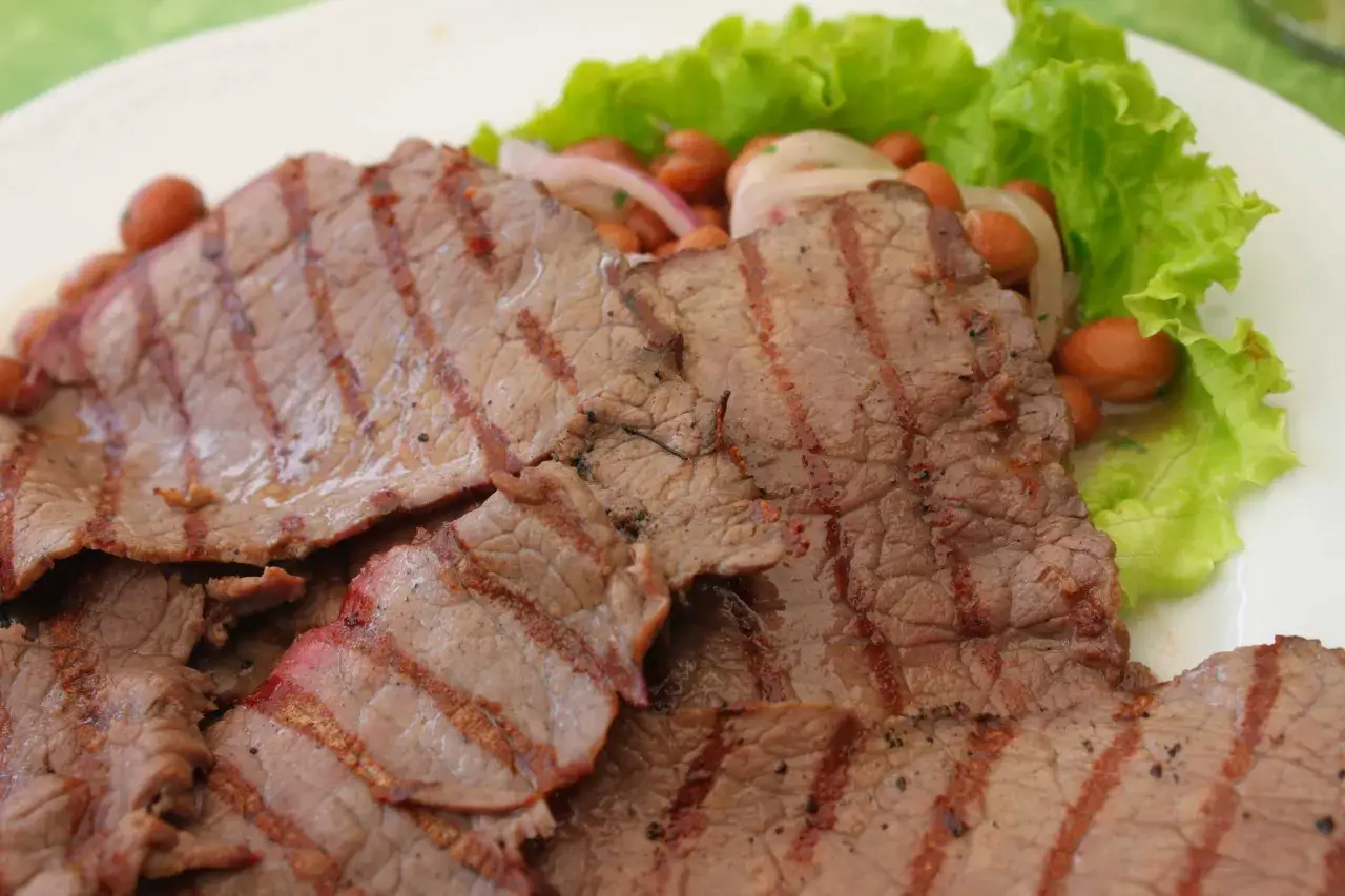 Fette di carne salada grigliata, servite con fagioli e lattuga. Un piatto che fa chiedere: carne salada cos'&egrave;?