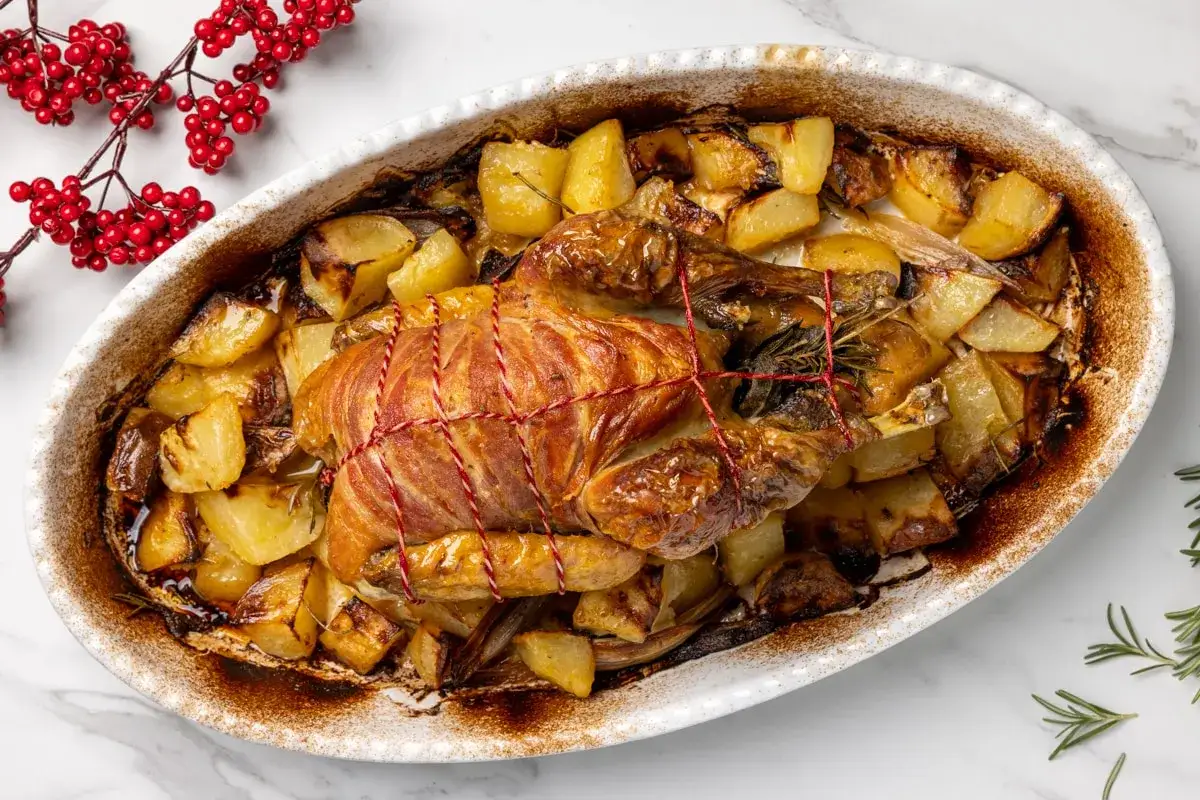 Faraona al forno dorata e succulenta, circondata da patate arrosto croccanti e profumate erbe aromatiche. Un piatto festivo pronto da gustare.