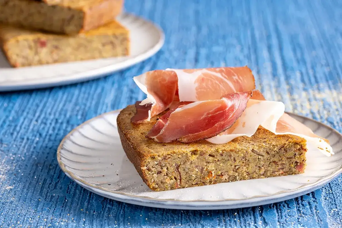 Fetta di torta salata con farina di grano saraceno, guarnita con prosciutto crudo. Perfetta per ricette facili e gustose.