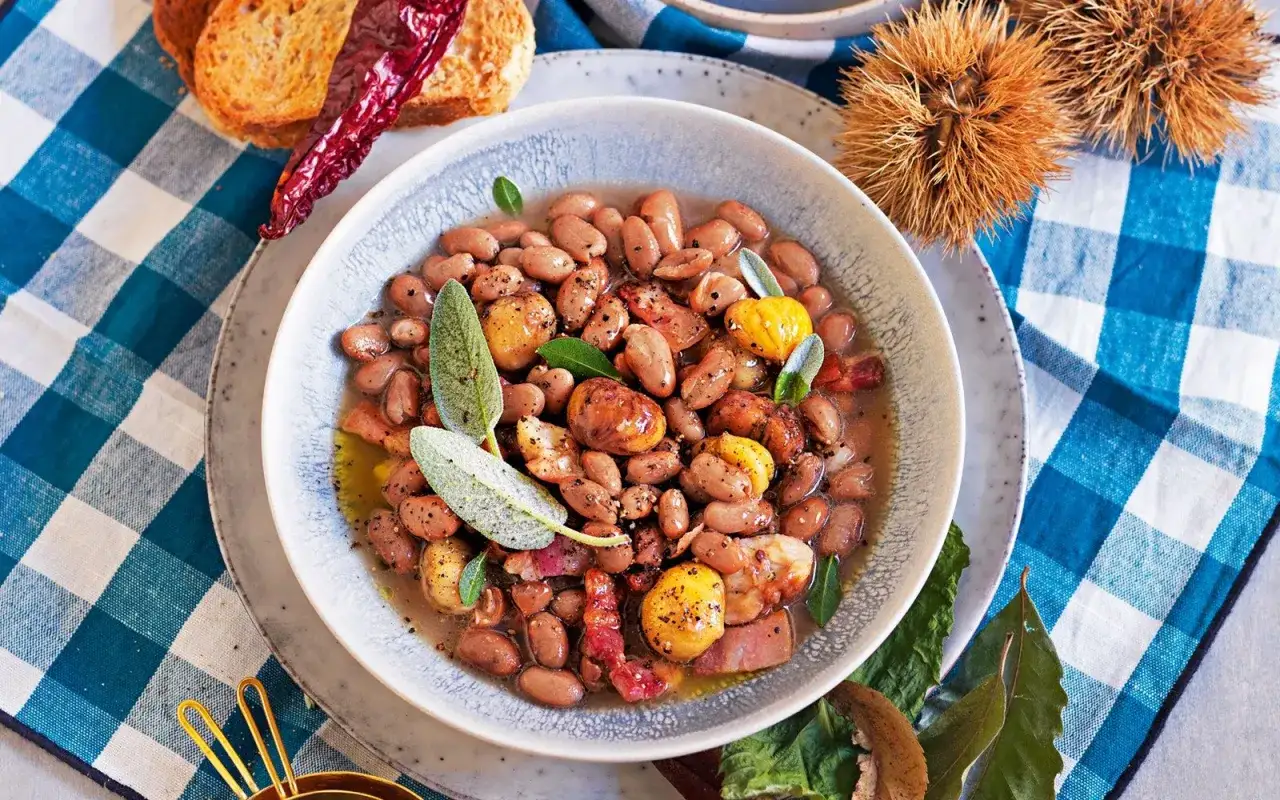 Piatto di fagioli stufati con castagne, pancetta e salvia. Un'idea su come cucinare i fagioli in modo gustoso, accompagnati da crostini e peperoncino.