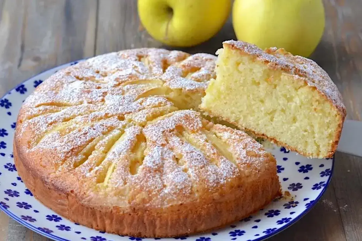 Una fetta di torta di mele e yogurt soffice, cosparsa di zucchero a velo, pronta per essere gustata.