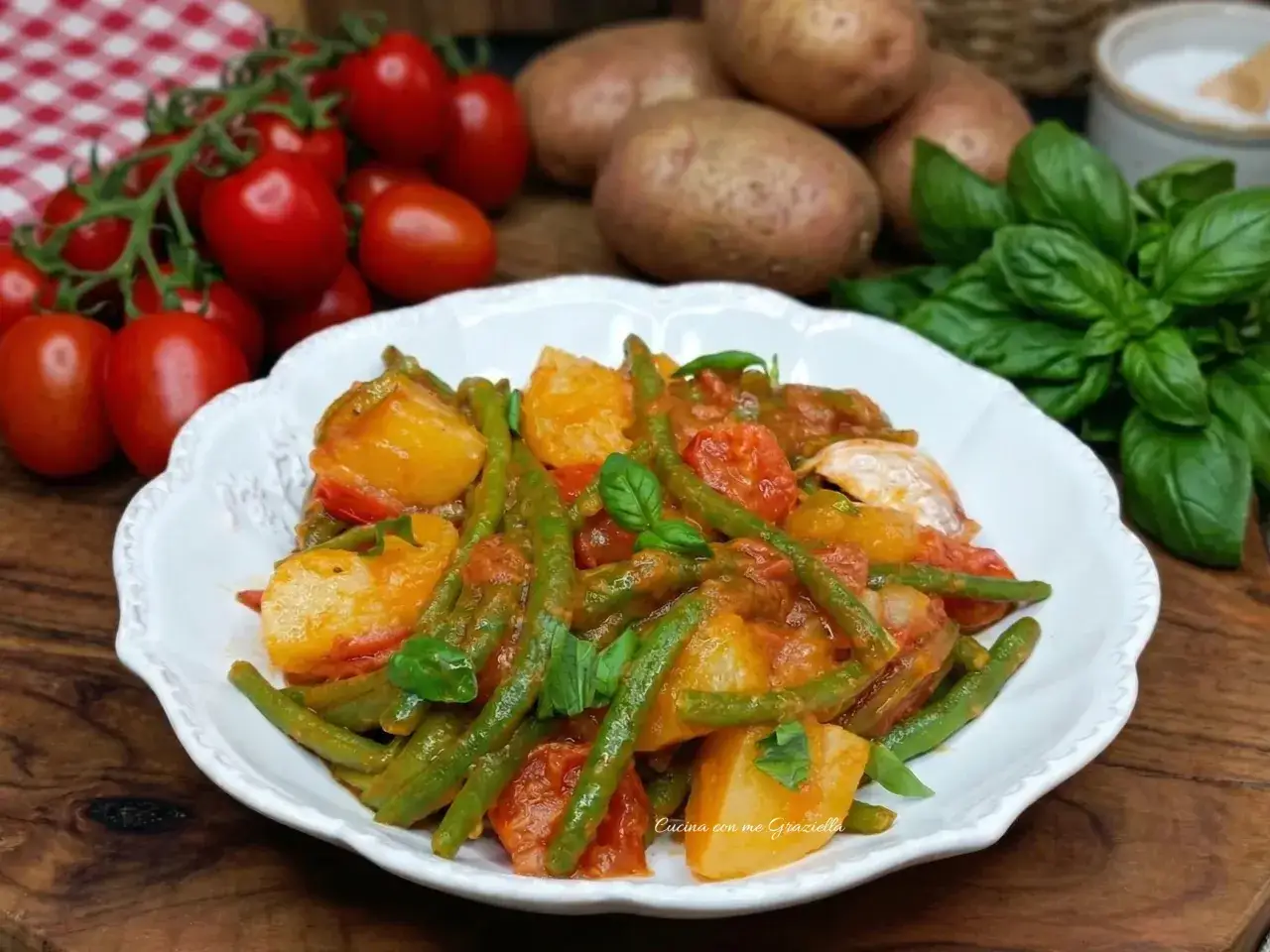 Un piatto invitante di fagiolini e patate alla pugliese, con pomodorini freschi e basilico.