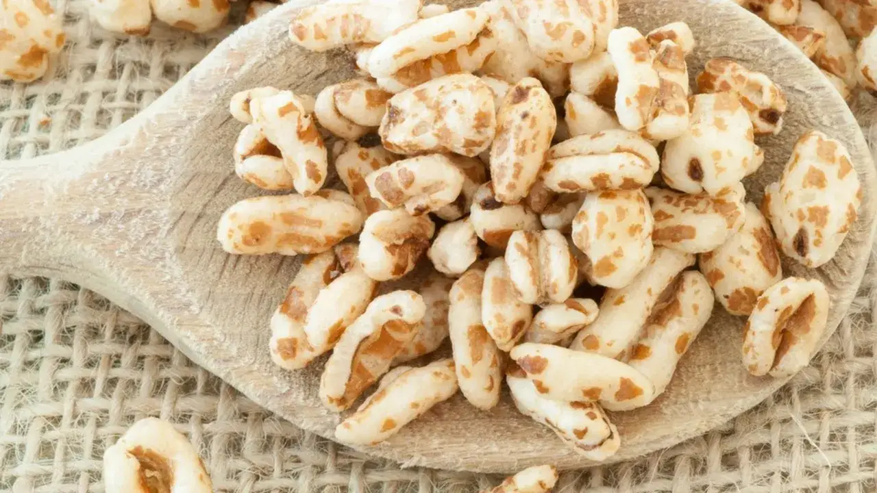 Farro soffiato su un cucchiaio di legno, perfetto per ricette croccanti e salutari.
