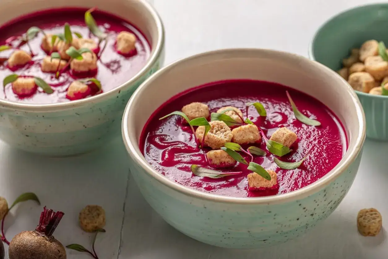 Zuppa cremosa di barbabietola rossa, guarnita con crostini e germogli. Un'idea per le tue barbabietola rossa ricette.