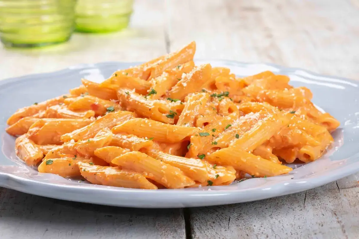 Penne cremose con sughi per pasta veloci e leggeri, guarnite con prezzemolo e parmigiano.