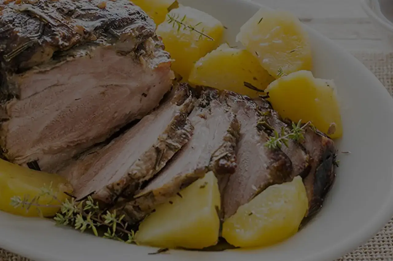 Succulenta coppa di maiale arrosto, affettata e servita con patate dorate e erbe aromatiche. Un piatto invitante e saporito.