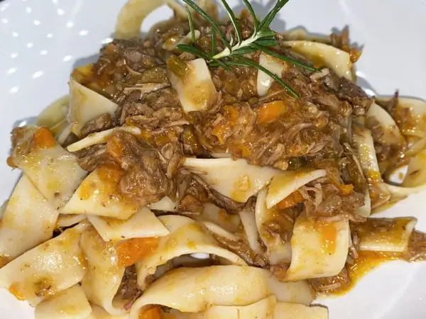 Pappardelle condite con un saporito ragù di cinghiale in bianco, guarnite con rosmarino fresco.